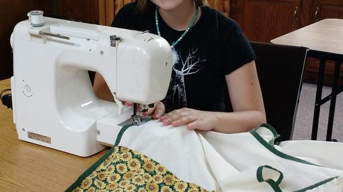 Youth Advisory Committee member Jessica Garbrick demonstrates the kind of apron contestants will have to create during Project Grange Fair.