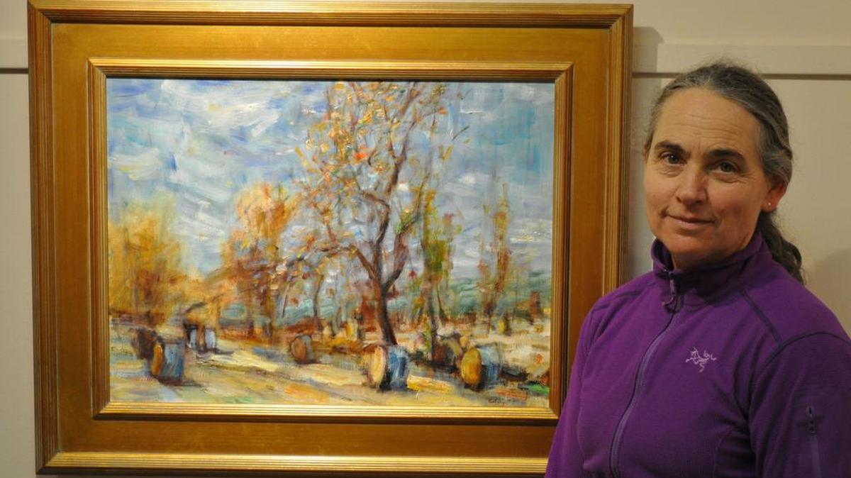 Artist Alice Kelsey poses next to “Round Bales — Warm Autumn Light,” an oil on canvas piece that is part of her upcoming exhibit at Foxdale Village Gallery.