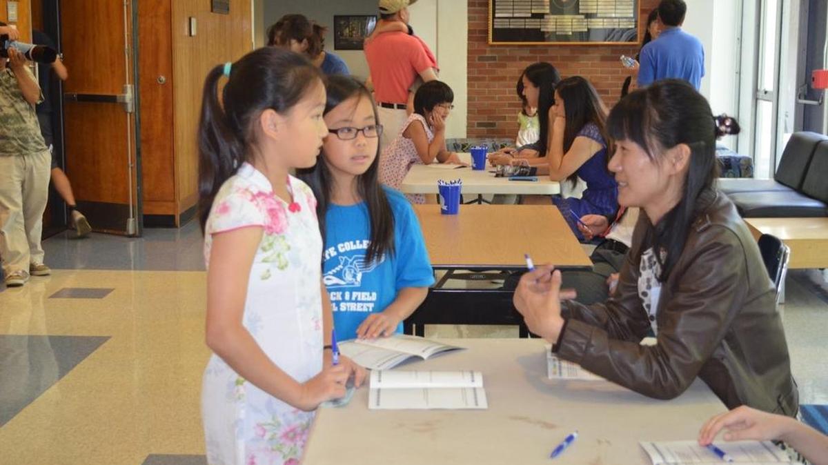 Penn State School of Music student volunteer Akina Kondoh helps children with a quiz that’s part of the Central Pennsylvania Music Teachers Association concert.