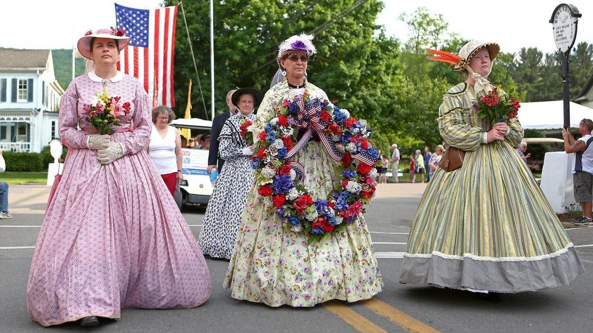 The ladies of Boalsburg Battery B carry flowers and a wreath as part of the Walk to the Cemetery to start the 2016 Memorial Day ceremony in Boalsburg.
