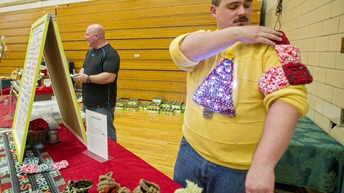 Damian Hyde shows off his crocheted holiday patterns, which can be pinned on to a sweater for ugly holiday sweater parties, during the Fall Craft and Gift Fair at Bald Eagle High School in November 2015.