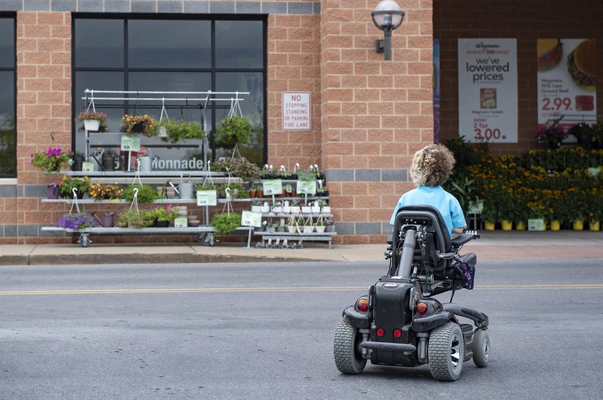 Dale Dyke, 16, heads into Wegmans for her shift as a cashier on Sunday, July 22, 2018.  Dale is working at Wegmans in hopes to save money to be able to buy an accessible car that she can drive.