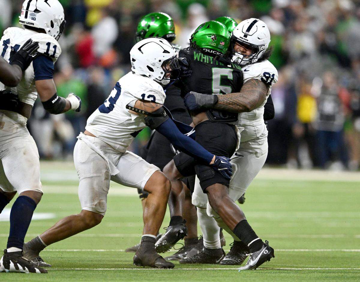 Penn State linebacker Tony Rojas and defensive tackle Dvon J-Thomas stop Oregon’s Ball carrier Noah Whittington during the Big Ten Championship game at Lucas Oil Stadium on Saturday, Dec. 7, 2024.