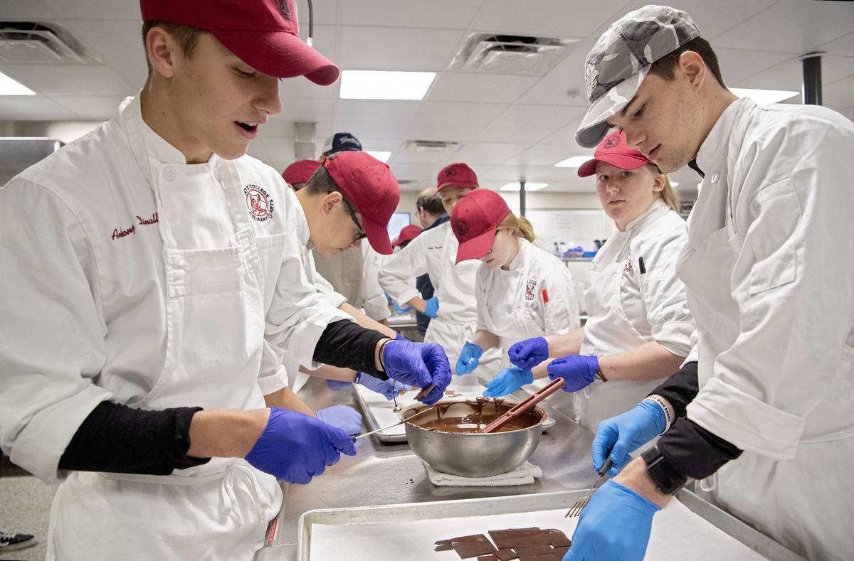 Students ranging from ninth grade to seniors in a culinary arts class at State College Area High School work together on Tuesday to make tempered chocolates. Chef Charles Niedermyer from Penn College visited the class to teach them about tempering.