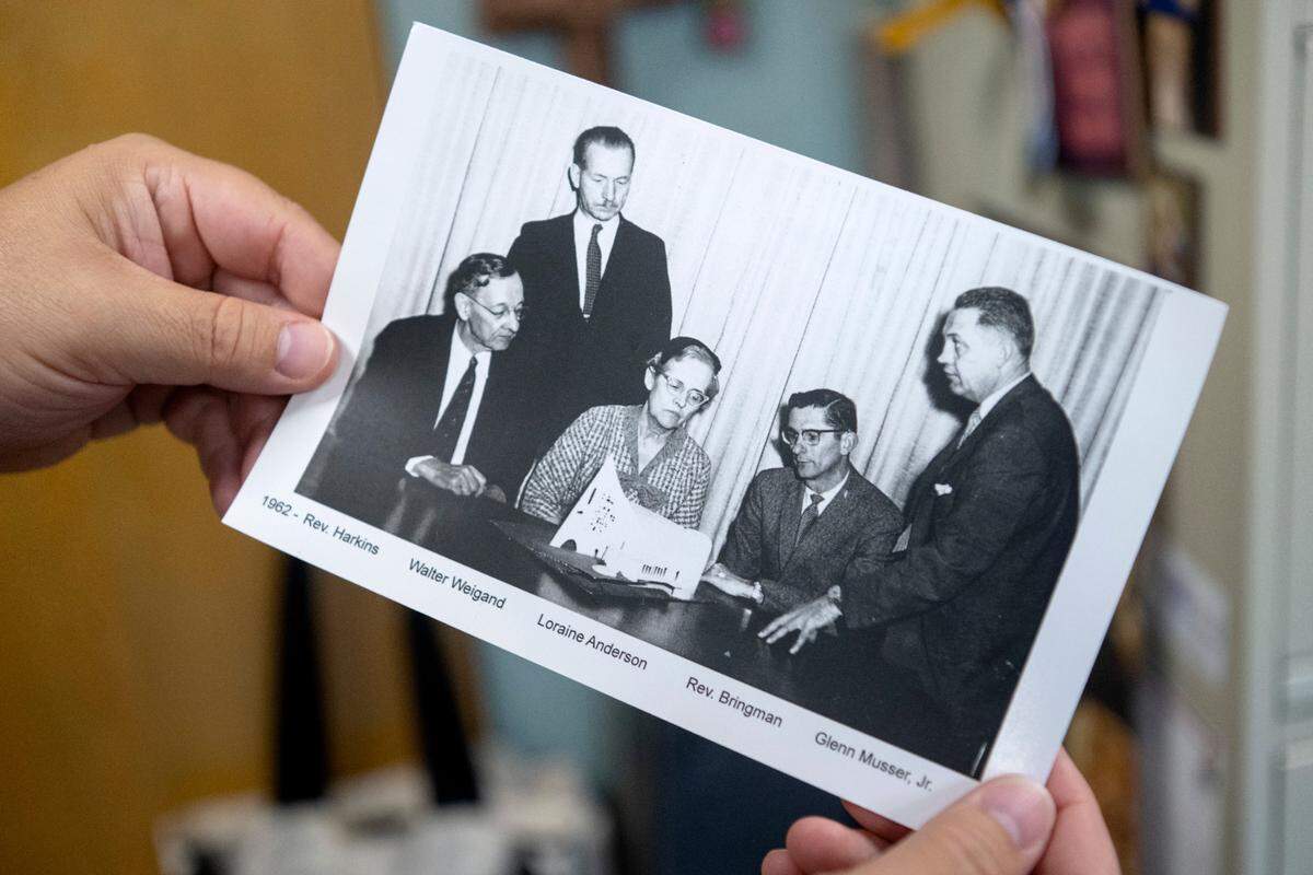 Senior Pastor Scott Schul shows a photograph of members of the Grace Lutheran building committee in 1962 looking at a diagram of the future church. The church is celebrating 125 years.