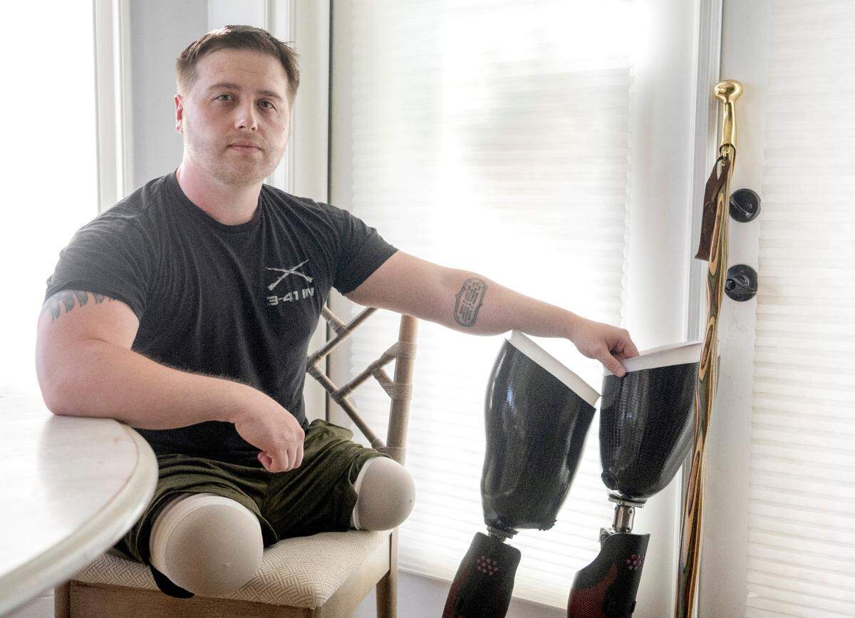 Adam Hartswick has a tattoo on his forearm of his four fellow Army soldiers that were killed on May 14, 2013 in Kandahar, Afghanistan, the same day he lost both of his legs. Hartswick sits in the kitchen the home he shares with wife Sara on Thursday, May 11, 2023.