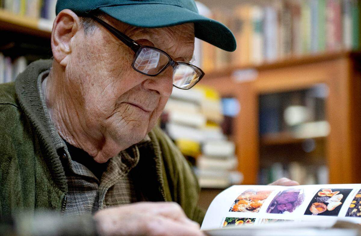 Bill Russell flips through a book looking for a specific mushroom during a gathering at Webster’s Bookstore Cafe on Monday, Sept. 9, 2024.