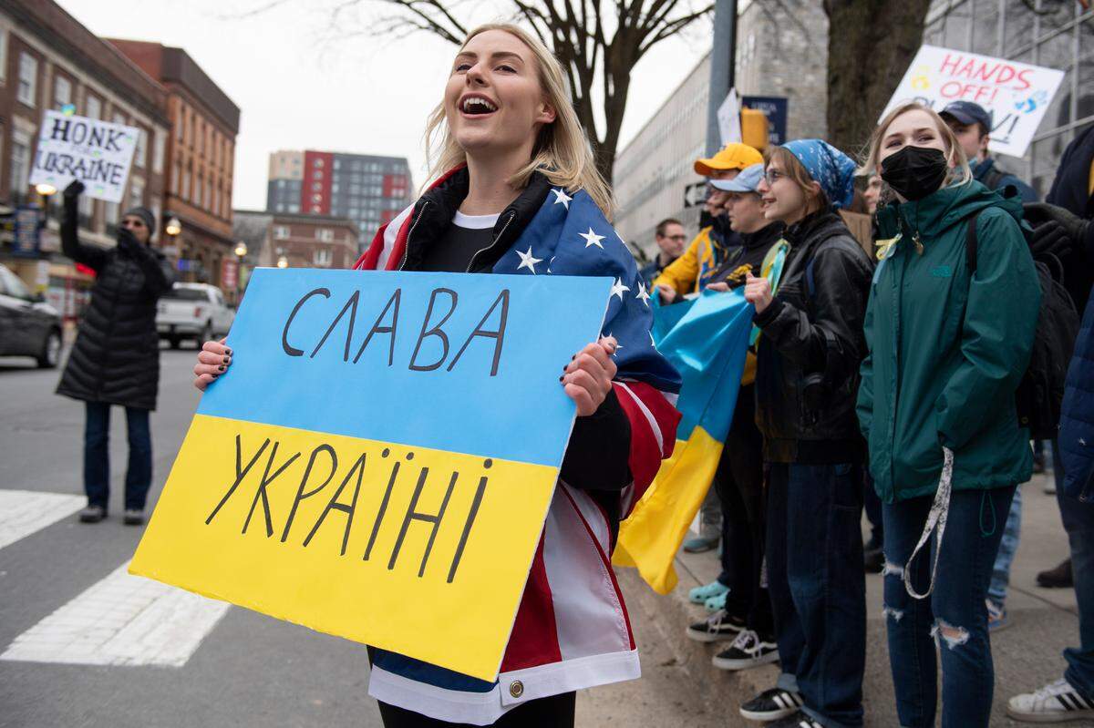 Sophia Datsko, a Penn State student, cheers as a car honks Thursday while holding a sign reading “glory to Ukraine” during a protest against the Russian invasion of Ukraine in front of the Allen Street Gates.