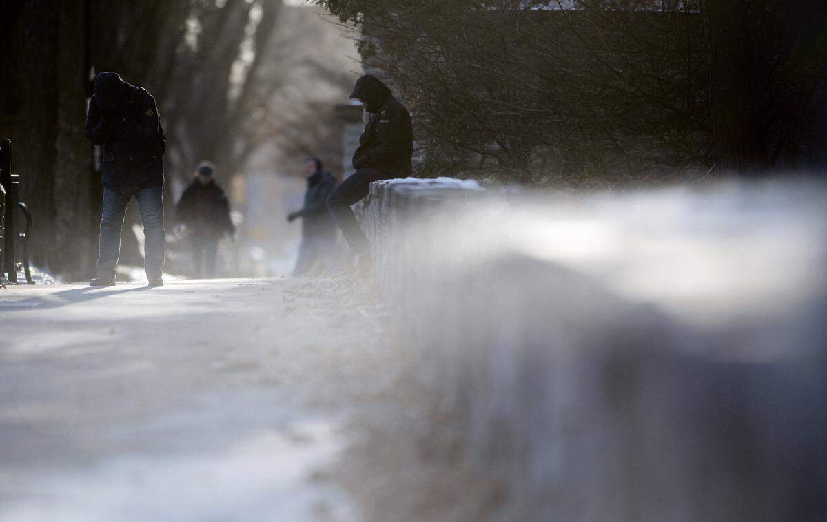 People shield themselves from the wind and cold as snow blows by the CATA bus stop on College Avenue in January 2018.