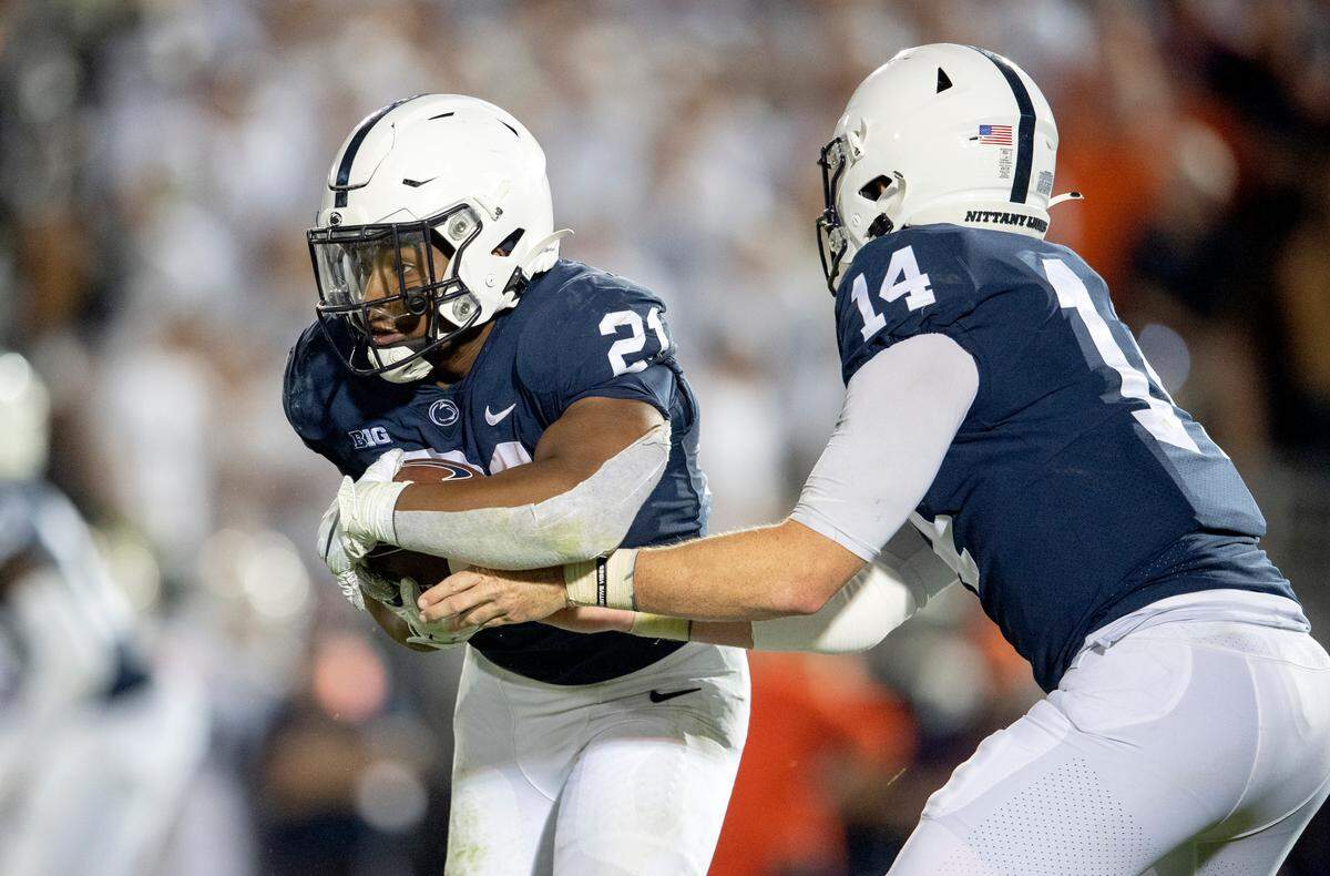 Penn State quarterback Sean Clifford hands off running back Noah Cain.