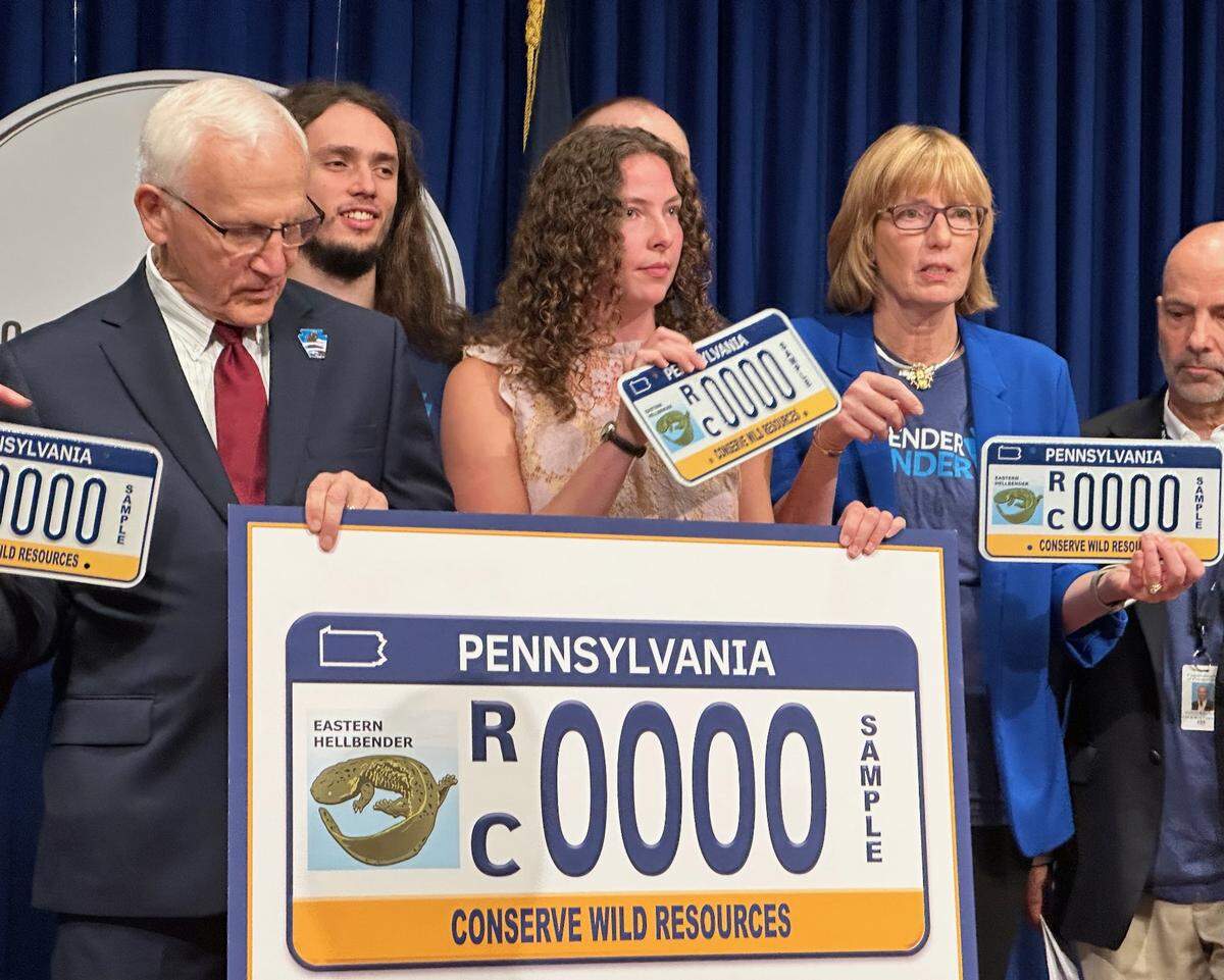 Among those gathered for a news conference on Monday announcing the availability of a license plate featuring an artist rendering of the Eastern Hellbender are Sen. Gene Yaw, who sponsored the legislation naming it the state amphibian; Emma Stone, who as a Carlisle high school student led a group to push for that designation for the hellbender, and Conservation and Natural Resources Secretary Cindy Dunn.