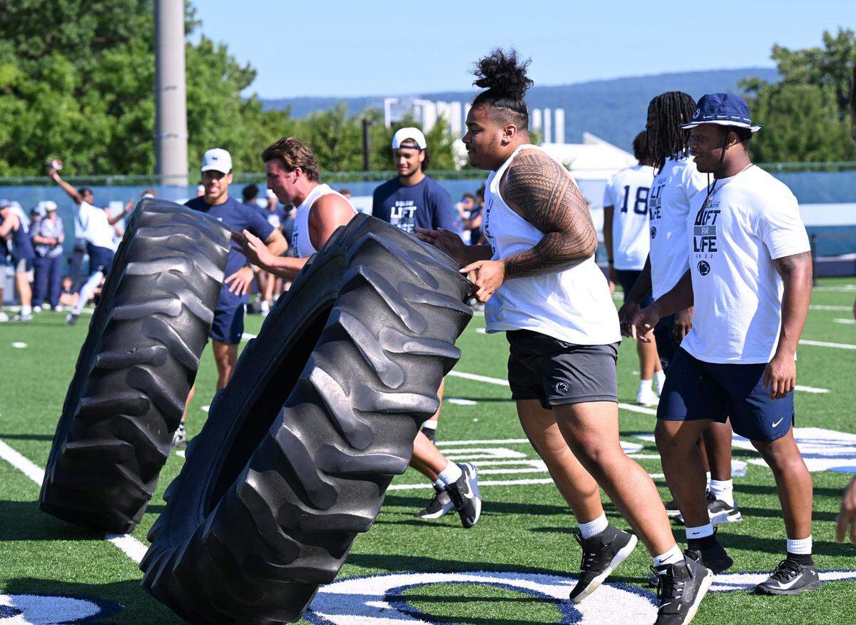 Penn State’s Dvon Ellies, right, flips a tire during the Nittany Lions annual Lift For Life event at University Park Thursday, June 30, 2022.