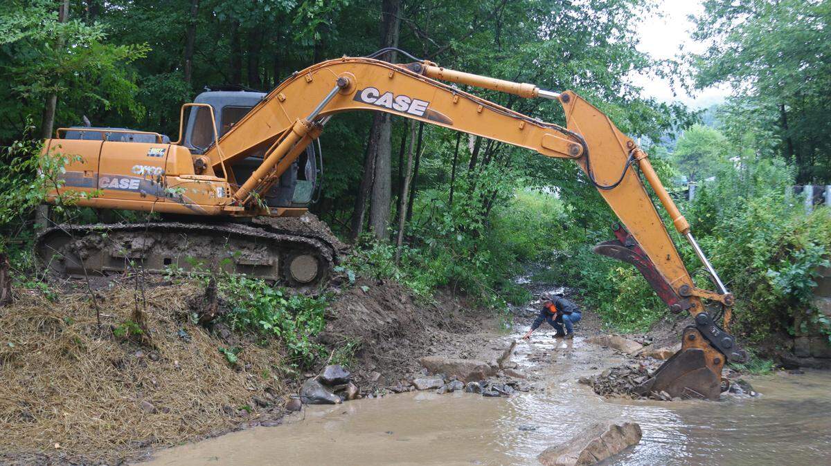 Trackhoe operator Terry Allen arranges boulders to create a stone deflector in Sparrow Run as Georgia Port of the US Fish and Wildlife Service checks the water depth.
