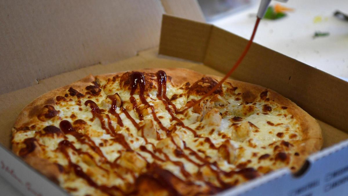 Weirdoughs Custom Pizzeria owner Joseph Boss puts the finishing touches on a barbecue chicken pizza on Sept. 22, 2020.