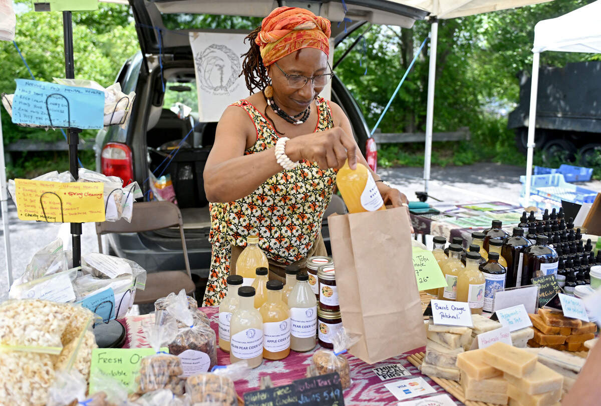 Yasoda Mensah bags an order for costumer at her stand Trifolia Natural Products and Botanicals at the Boalsburg Farmers Market on Tuesday, June 23, 2026.