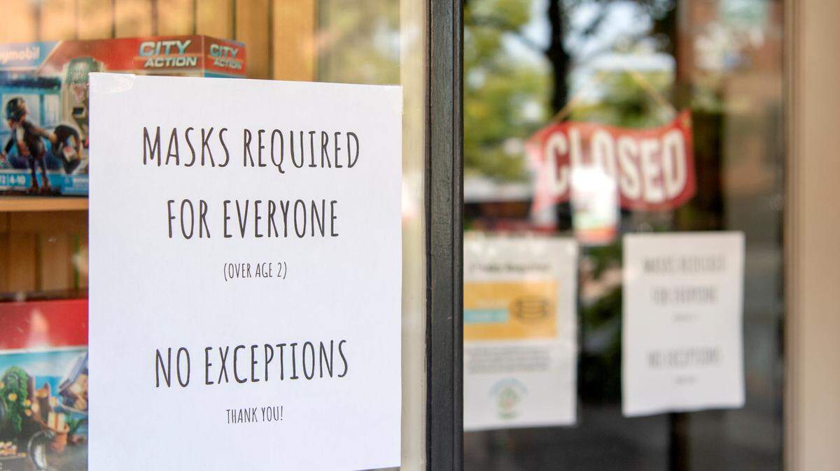 Signs about masks hang on the entrance to Growing Tree Toys in September.