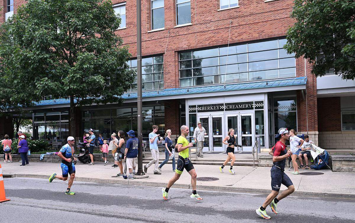 Participants in the Ironman 70.3 Pennsylvania Happy Valley run past the Berkey Creamery on the Penn State campus Sunday, July 2, 2023.