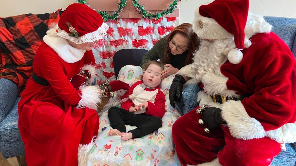 Santa and Mrs. Claus sit with a child and his mother at the Children’s Home of Pittsburgh.