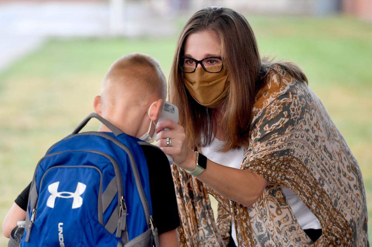 Wingate Elementary counselor Monica Graham checks the temperatures of students as they arrive for the first day of school on Tuesday, Aug. 25, 2020.