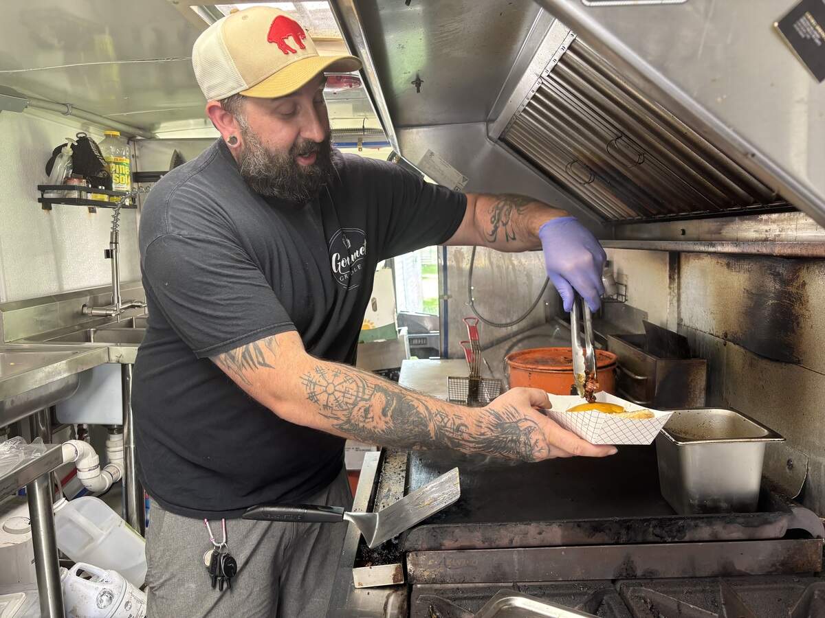 Brandtly Ward puts bacon on the BCB Burger, which is a staple menu item at Gourmet Griddle, inside his food truck on Monday, June 15, 2026.