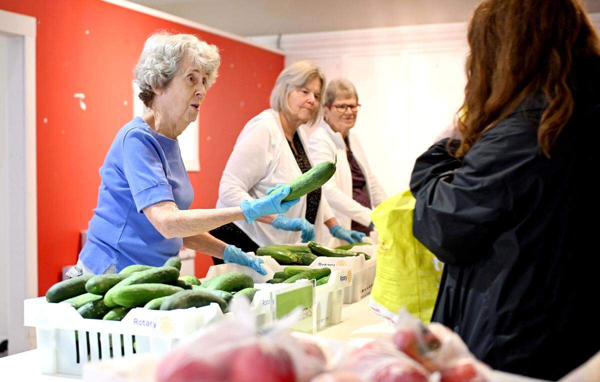 Volunteer Maryann Frankenberg hands out cucumbers during the State College Food Bank No-Cost Produce Market on Tuesday, July 1, 2025 at the Nittany Mall.