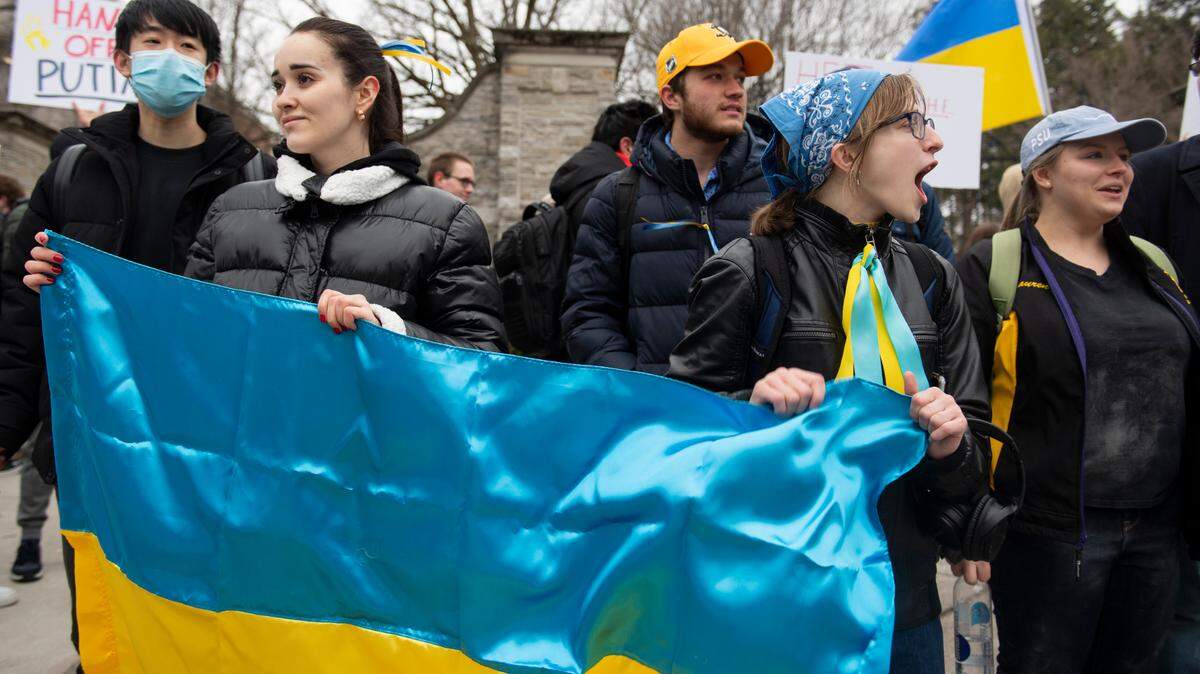 Nelia Mihai (left) and Hannah Scholze (right) hold a Ukrainian flag during a protest against the Russian invasion of Ukraine in front of the Allen Street Gates on Thursday, Feb. 24, 2022 in State College, Pa. State College Borough is looking to add its first official “Sister City” in Nizhyn, Ukraine.