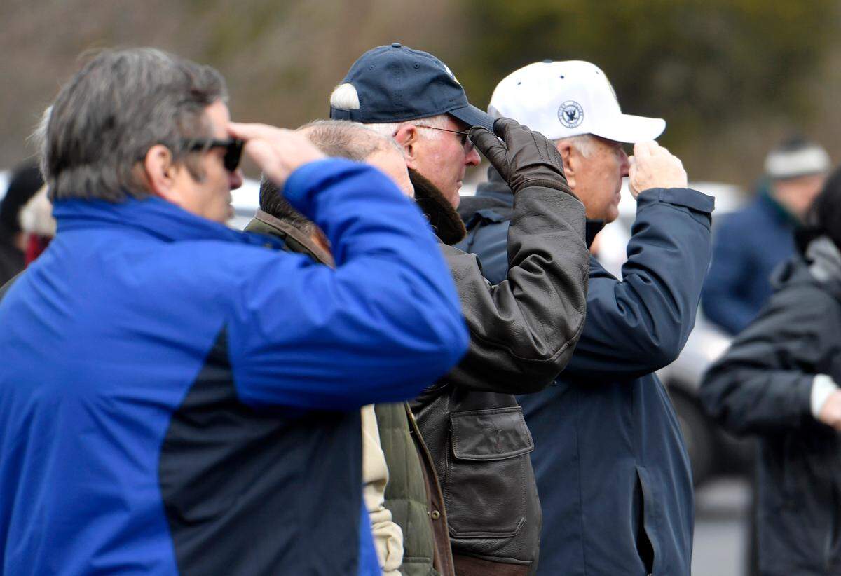 Community members salute Tuesday as taps is played during the Pennsylvania Military Museum’s Pearl Harbor Day commemoration next to the guns of the battleship USS Pennsylvania.