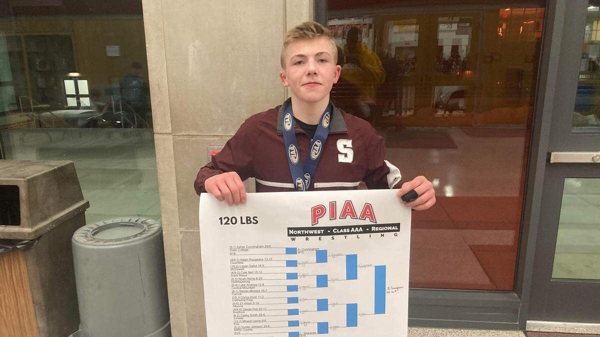 State College wrestler Asher Cunningham shows off gold medal and bracket, following his first-place finish in the PIAA Northwest 3A Regional.