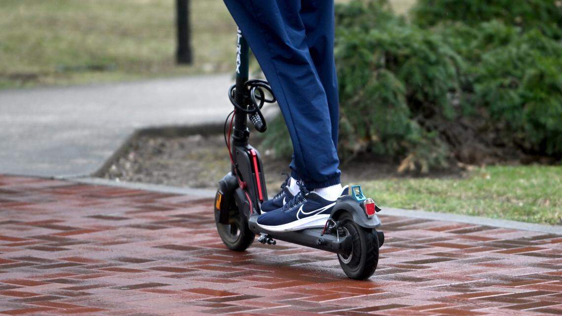 A person rides a scooter along Pollock Road on the Penn State campus on March 31, 2023.