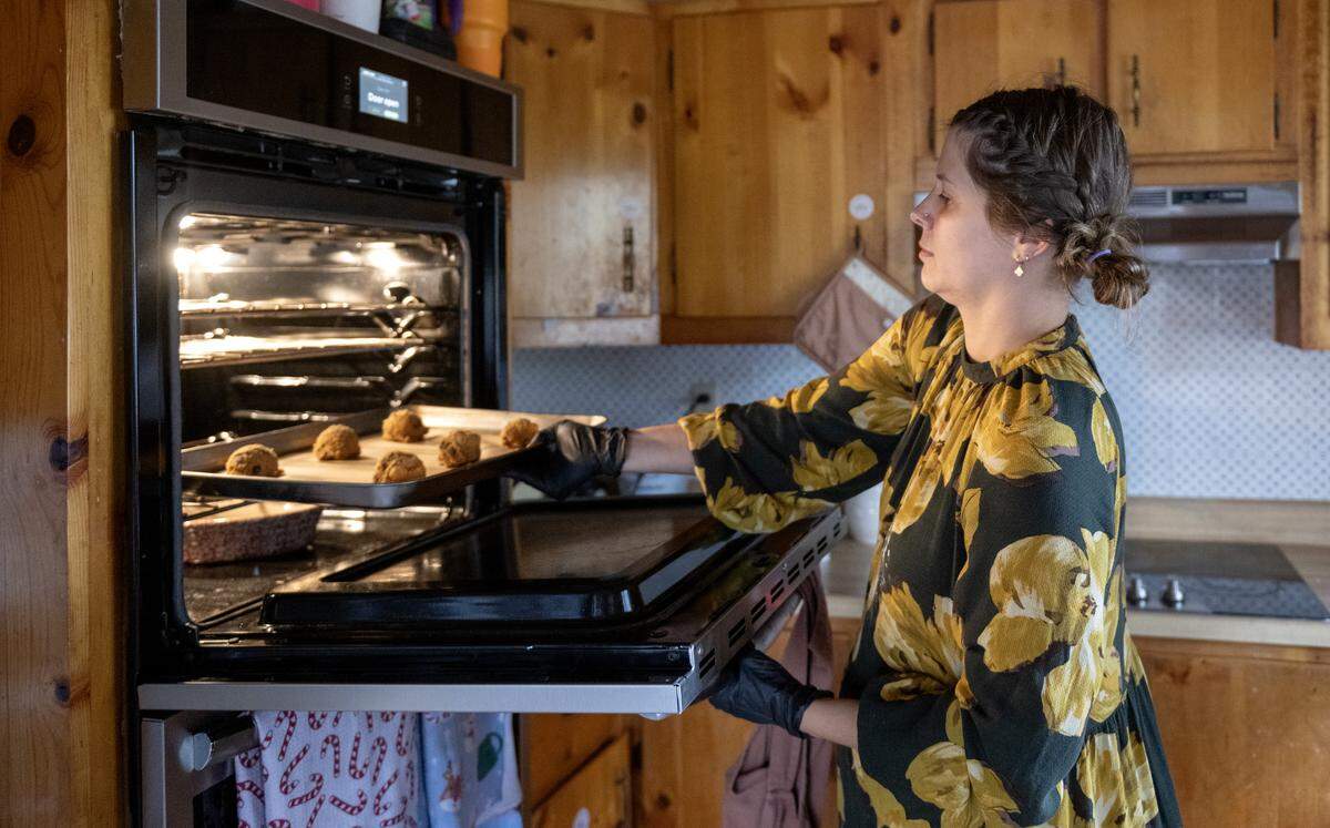 Alyssa Burns of Blackberry Cottage Bake Shoppe puts a batch of chocolate chip cookies in the oven on Friday, Nov. 14, 2025. 