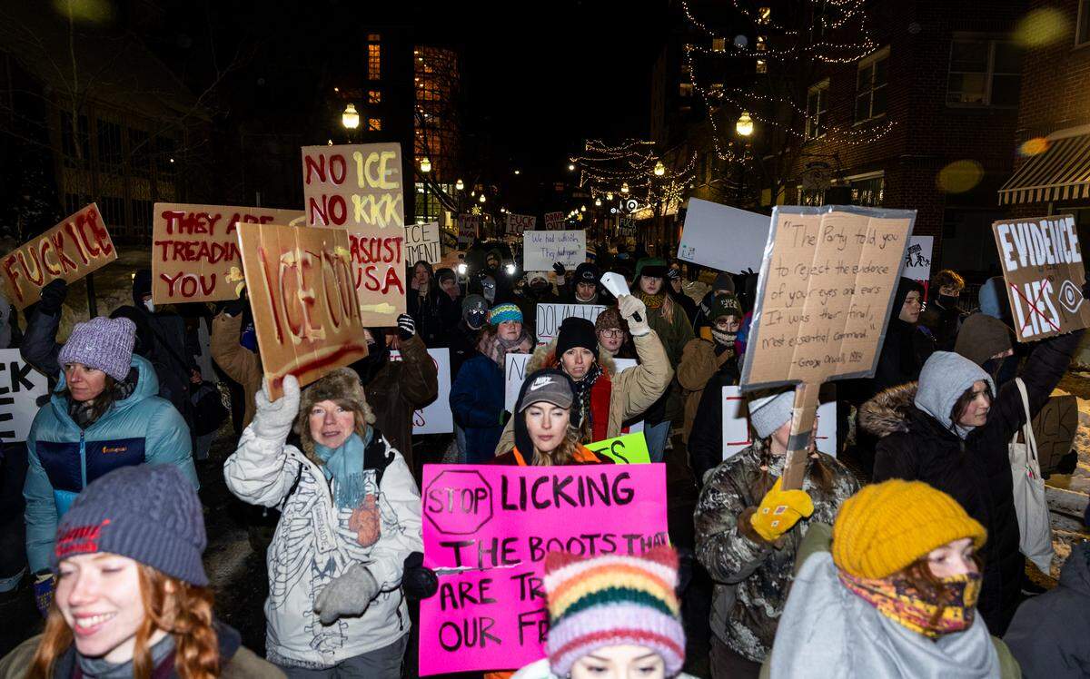 Anti-ICE protesters chant and hold up signs as they march through downtown State College on Monday.