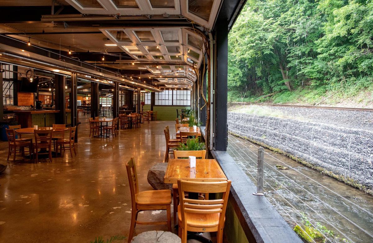 Garage doors open up for visitor to sit along the creek at Axemann Brewery in the Titan Energy Park.