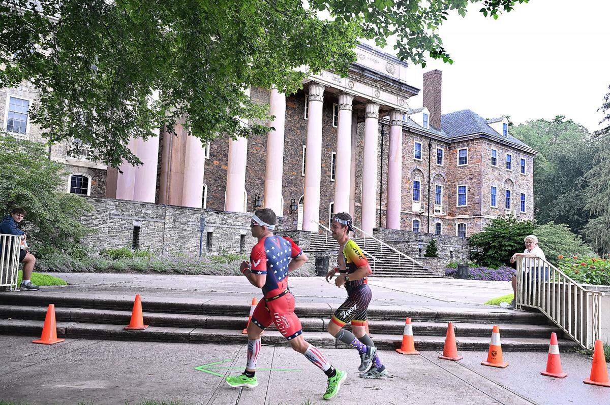 Participants in the Ironman 70.3 Pennsylvania Happy Valley run past Old Main on the Penn State campus Sunday, July 2, 2023.