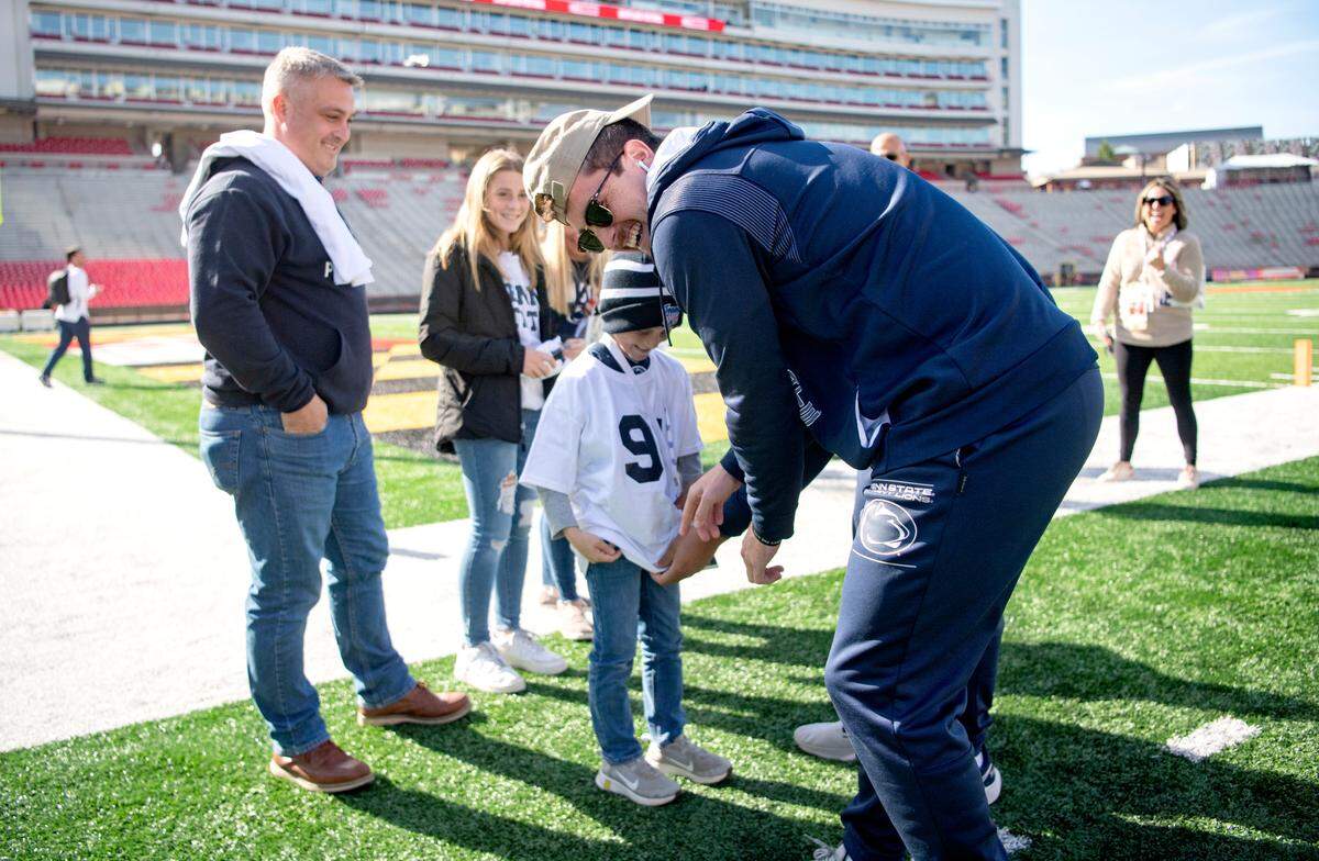 Penn State quarterback Sean Clifford jokes with Sawyer Bell, 9, to keep on the 14 jersey he was wearing before he put on a Dvon Ellies t-shirt at Maryland Stadium on Saturday, Nov. 6, 2021. Sawyer is part of team IMPACT.