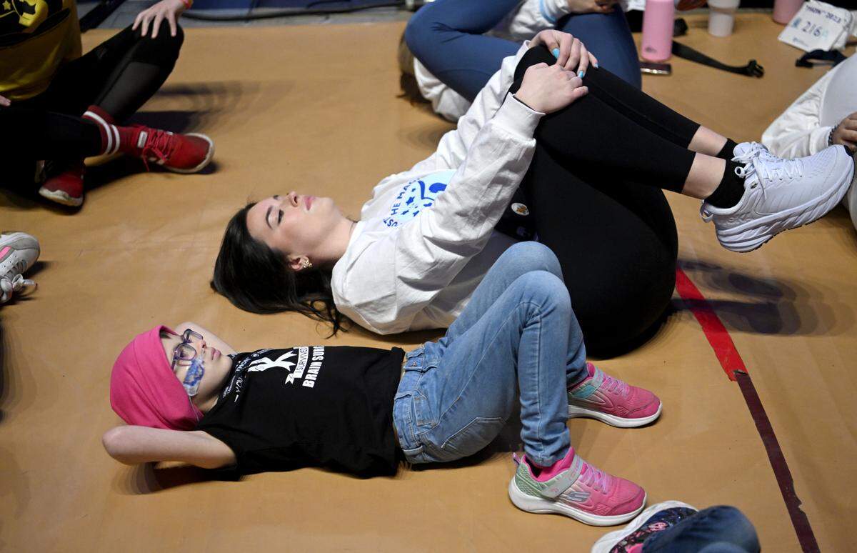 Brooke Ross, 9, lays next to Alicia Young as they wait for the stand up for the 46 hour Penn State IFC/Panhellenic Dance Marathon on Friday, Feb. 17, 2023 at the Bryce Jordan Center.