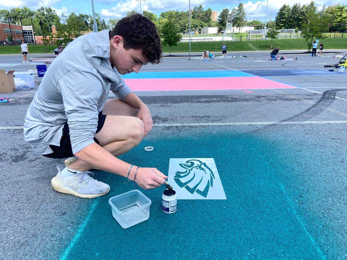 Sam Jacobs, a senior, painting the Philadelphia Eagles logo onto his parking spot at the State High senior lot on Wednesday, Aug. 18, 2023.