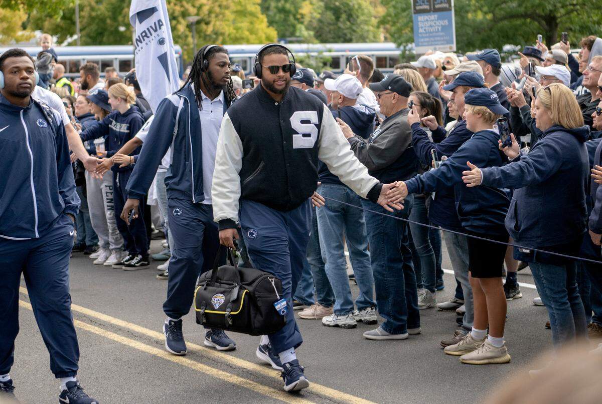 Penn State defensive tackle PJ Mustipher high fives fans as he and the team arrive at Beaver Stadium for the game on Saturday, Sept. 24, 2022.