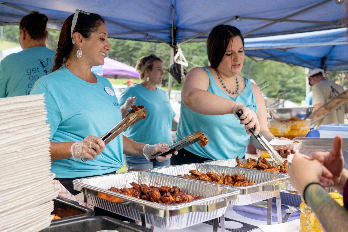 Juniper Village’s Liz Plozner-Chalfa laughs as she gets wings ready for an order during the finals for WingFest at Tussey Mountain on Thursday, Aug. 4, 2022.