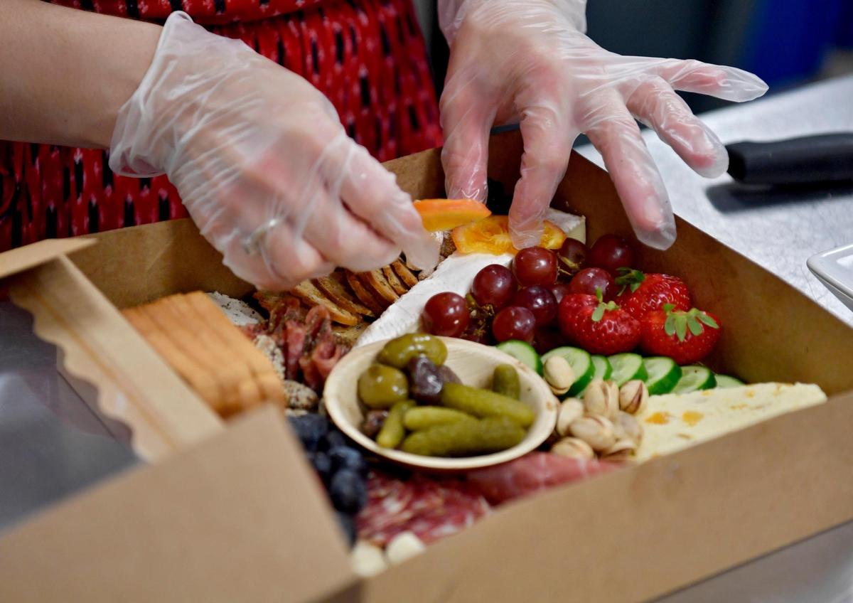 Amanda Cruz of The Gourmet Girl Personal Chef Service places some fruit on a slice of brie in a grazing box for a client on Monday, August 3, 2020.
