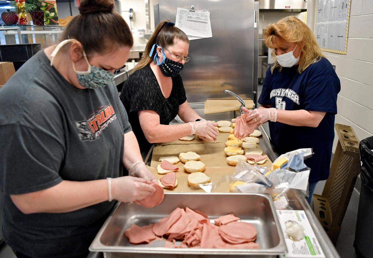 Volunteers Mandy Schaffer, Cindy Vasquez and Lisa Shone work together to make hundreds of ham and cheese sandwiches for the YMCA lunch program on Thursday, April 16, 2020 at the Philipsburg-Osceola Middle School.