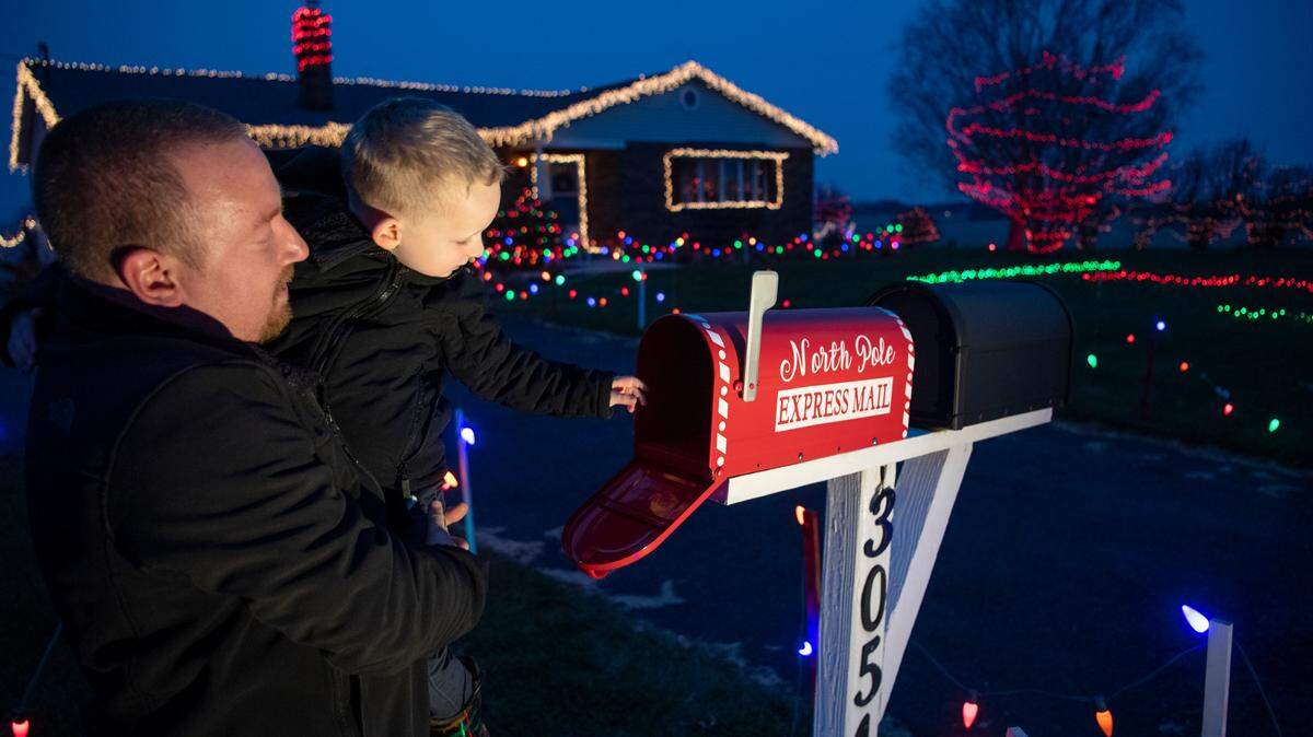 Daniel Forster and his son Zayden, 3, check the North Pole express mailbox for letters to Santa at their decorated home on West Whitehall Road on Dec. 9.