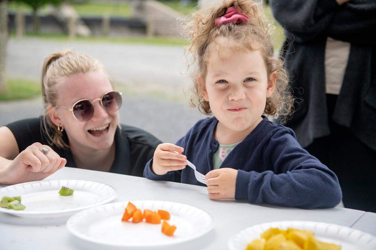 Hannah Myers from the YMCA laughs with Stella Evans, 4, as she tries kiwi and other fruits during the Free to Be Me Summer Tour event at the Cold Stream Dam on Friday, June 10, 2022.