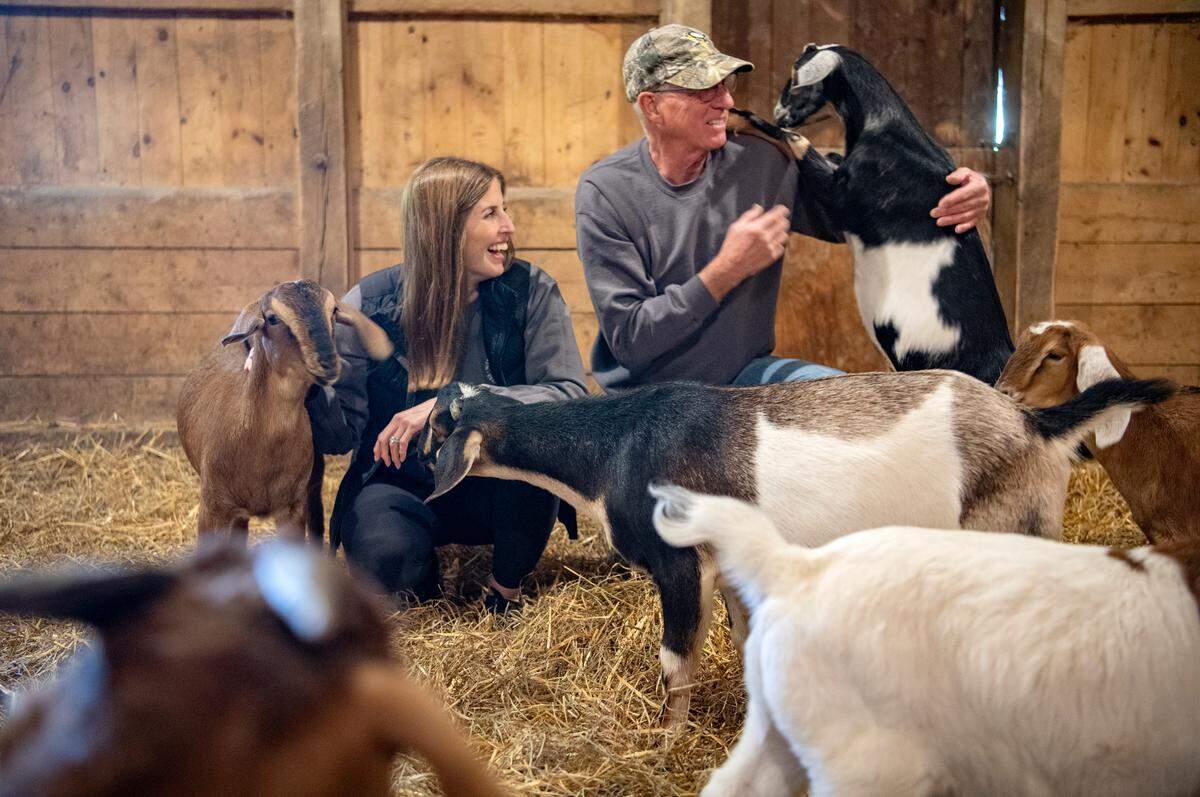 Tara and Mike Immel laugh as they visit with their goats who star in Goat Yoga at Nittany Meadow Farm.