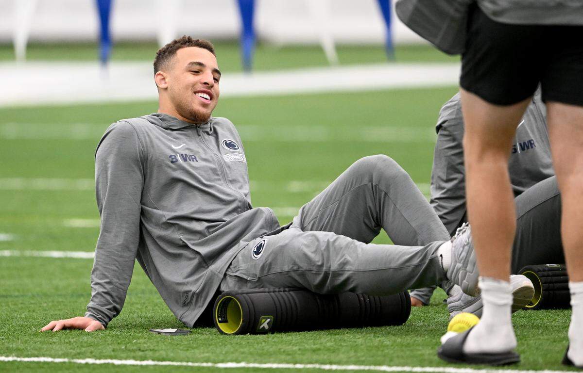 Wide receiver Parker Washington talks with teammates as he stretches at Penn State football’s Pro Day on Friday, March 24, 2023.