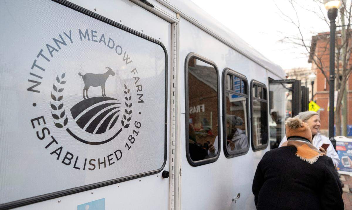 Visitors laugh as they peak in the windows of Nittany Meadow Farm’s new Goats2Go bus on Friday, Nov. 18, 2022 in downtown State College.