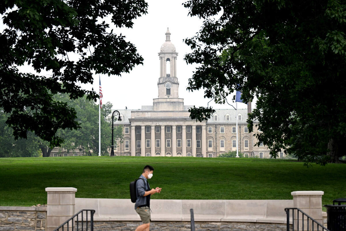 A person wearing a mask walks along College Avenue in front of Old Main on Thursday, July 16, 2026. Wildfire smoke from Canada caused unhealthy air levels in Centre County.