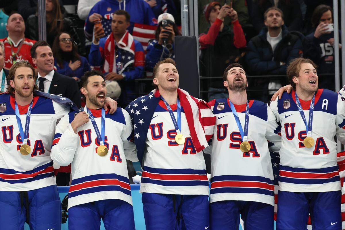MILAN, ITALY - FEBRUARY 22: Golds medalists Noah Hanifin #15, Vincent Trocheck #16, Matthew Tkachuk #19, Dylan Larkin #21 and Charlie McAvoy #25 of Team United States listen to the national anthem during the medal ceremony for Men's Ice Hockey following their gold-medal win during the Men's Gold Medal match between Canada and the United States on day 16 of the Milano Cortina 2026 Winter Olympic games at Milano Santagiulia Ice Hockey Arena on February 22, 2026 in Milan, Italy. (Photo by Bruce Bennett/Getty Images)