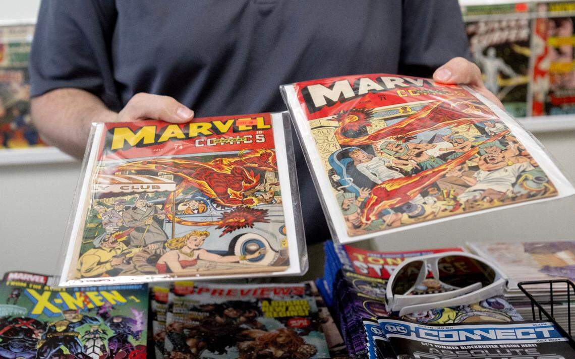 Justin Behrens shows two old Marvel comic at his shop Comic Cove on Monday, May 20, 2024.