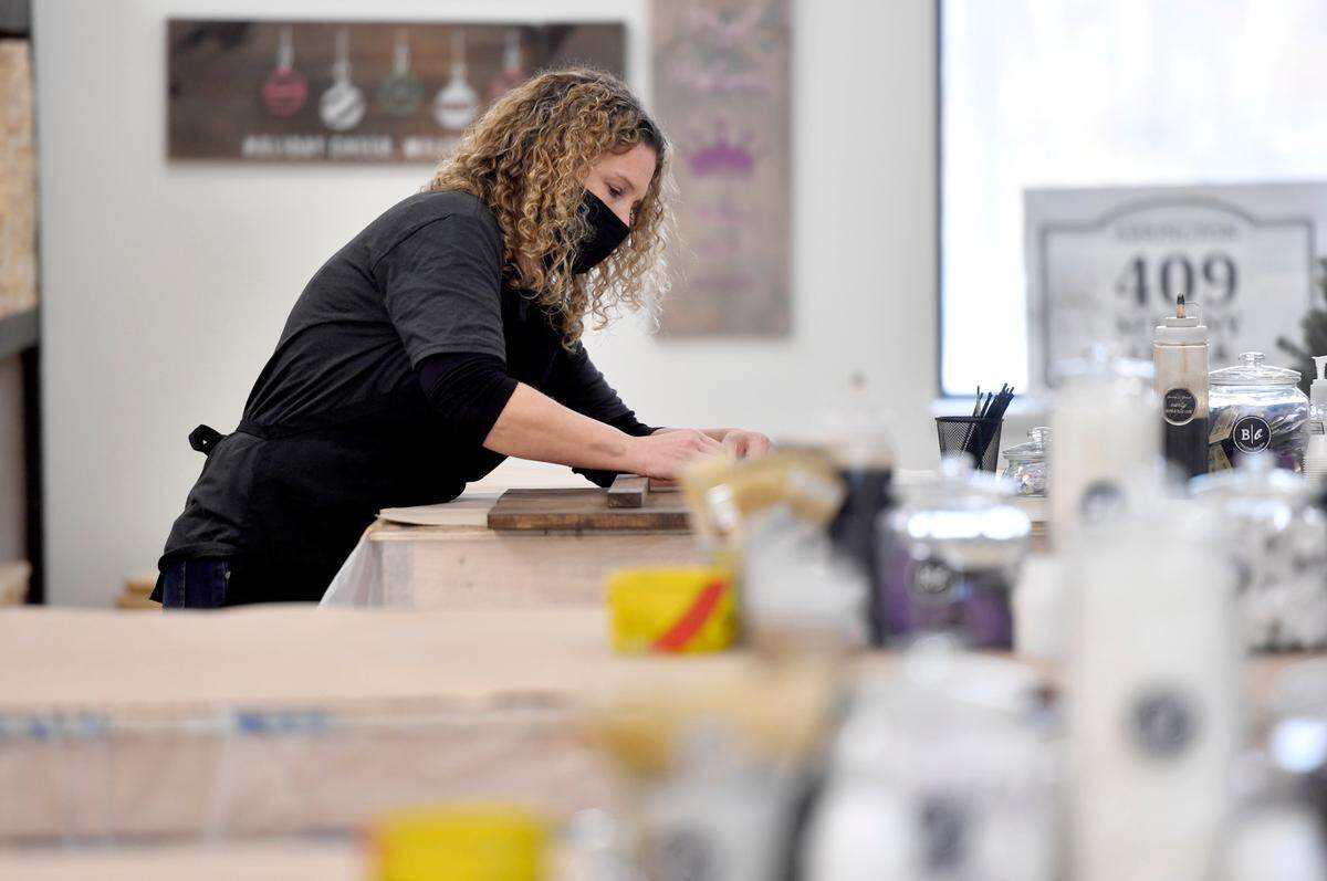 Lyndsay Nybeck installs the hooks on a new wood sign at Board and Brush creative studio State College on Thursday, Dec. 10, 2020.