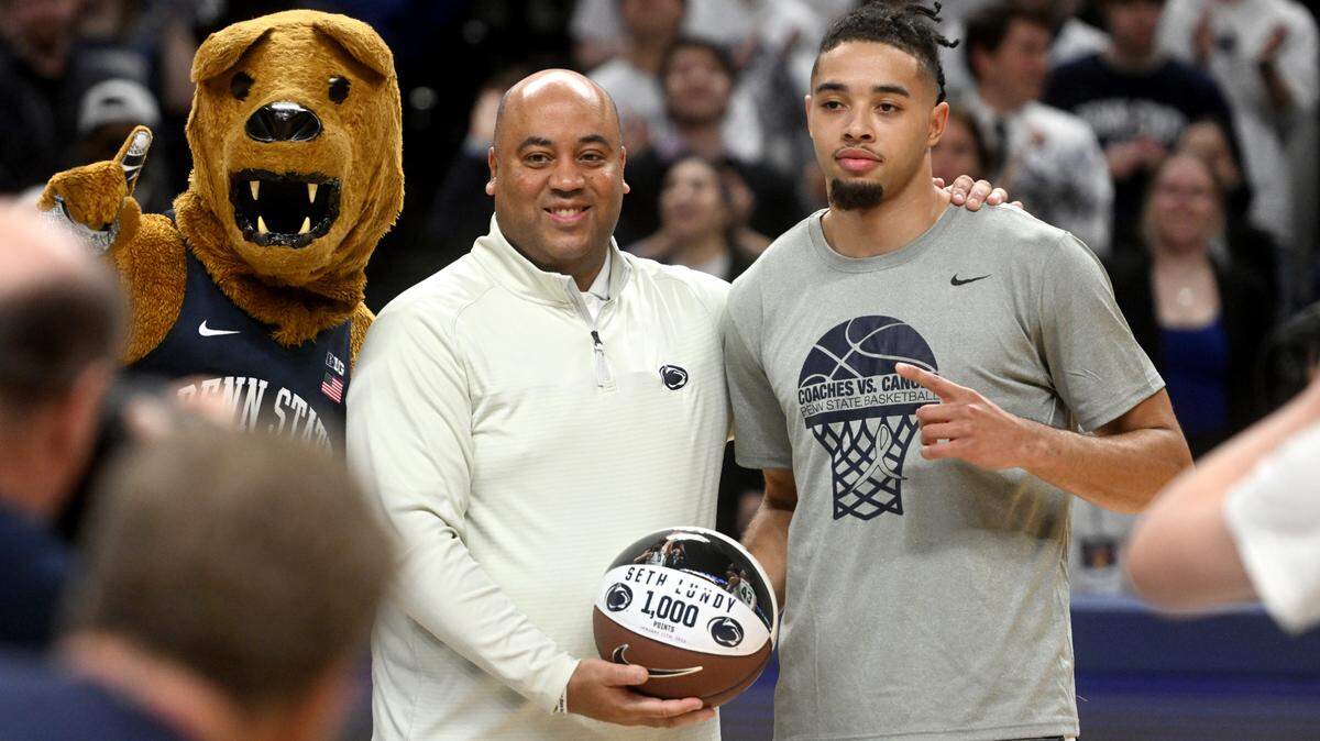Penn State men’s basketball coach Micah Shrewsberry gives Seth Lundy a basketball commemorating his 1,000 points before the game against Nebraska on Jan. 21.